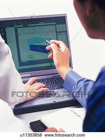 Stock Photo - Businessman and businesswoman working with a computer at the desk, Portrait, Rear View, High Angle View. Fotosearch