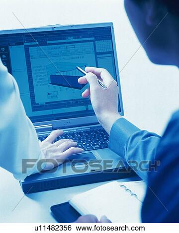 Stock Photograph - Businessman and businesswoman working with a computer at the desk, Portrait, Rear View, Toned Image. Fotosearch