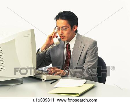 Stock Image - Businessman working with a computer at the desk, Portrait, Side View. Fotosearch
