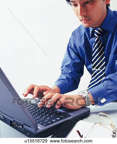 Stock Photo - Businessman working with a computer at the desk, Portrait, High Angle View. Fotosearch