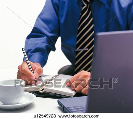 Stock Photo - Businessman writing down on a scheduler, Portrait, Front View. Fotosearch
