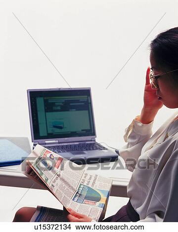 Businesswoman sitting and reading news paper at the desk, Portrait, Side View View Large Photo Image Picture - Businesswoman sitting and reading news paper at the desk, Portrait, Side View. Fotosearch