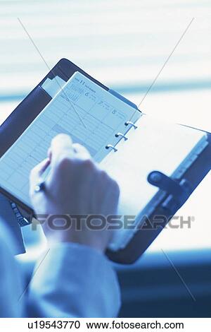 Stock Image - Hand making note on a scheduler, High Angle View, Toned Image. Fotosearch