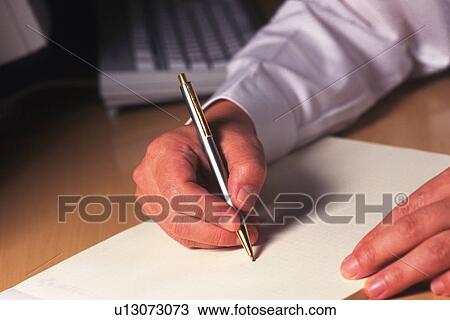 Stock Image - Hand writing down note on a piece of paper, High Angle View. Fotosearch
