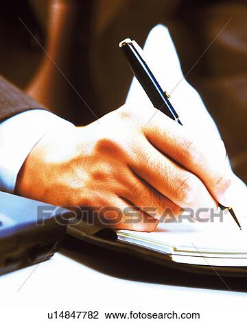 Stock Image - Hand writing down on a scheduler, Close Up, Toned Image. Fotosearch