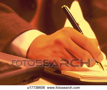 Stock Photograph - Hand writing down on a scheduler, Close Up, Toned Image. Fotosearch