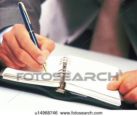 Stock Photograph - Hand writing down on a scheduler, Front View. Fotosearch