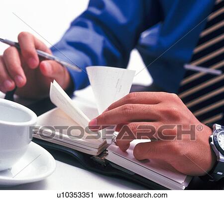 Stock Image - Hands flipping the pages of the scheduler, High Angle View. Fotosearch