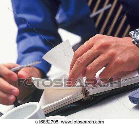 Stock Photography - Hands flipping the pages of the scheduler, High Angle View. Fotosearch