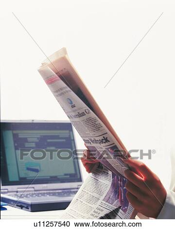 Stock Image - Hands holding news paper at the desk, Portrait, Side View. Fotosearch