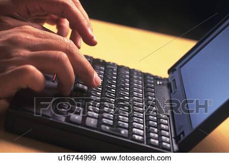 Stock Photo - Hands typing on a laptop computer keyboard, High Angle View. Fotosearch