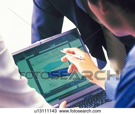 Stock Image - Three people working together with a computer at the desk, Portrait, Rear View. Fotosearch