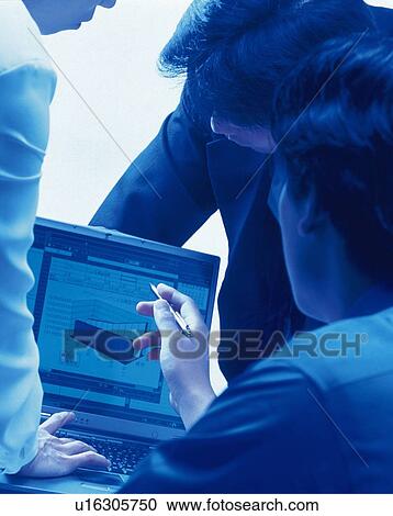 Stock Image - Three people working together with a computer at the desk, Portrait, Rear View, Toned Image. Fotosearch