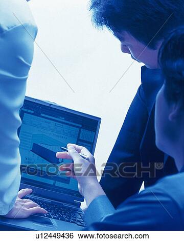 Stock Photograph - Three people working together with a computer at the desk, Portrait, Rear View, Toned Image. Fotosearch