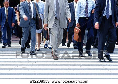 Stock Image - Business people crossing at the crosswalk, front view, Tokyo, Japan. Fotosearch