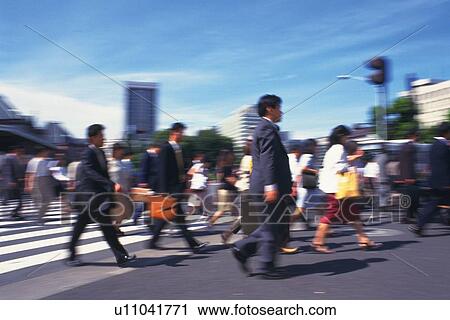 Stock Image - Business people intersecting at the crosswalk, side view, blurred motion, Tokyo, Japan. Fotosearch
