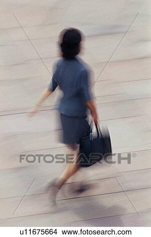 Picture - Businesswoman walking and holding bag, high angle view, blurred motion, Tokyo, Japan. Fotosearch