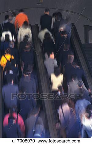 Stock Image - People riding escalators, low angle view, blurred motion, Tokyo, Japan. Fotosearch