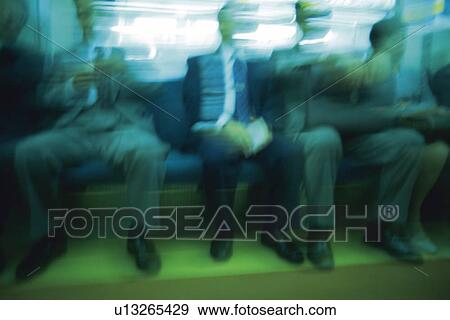 Stock Photo - People sitting down on seat on train, low angle view, blurred motion, Tokyo, Japan. Fotosearch