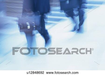 Stock Image - Two men crossing at the crosswalk, high angle view, blurred motion, Tokyo, Japan. Fotosearch