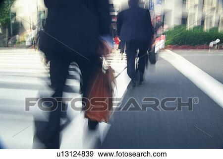 Stock Photo - Two men crossing at the crosswalk, rear view, blurred motion, Tokyo, Japan. Fotosearch