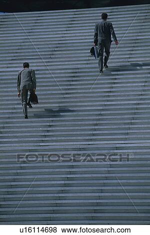 Stock Photo - Two men walking up stairs, rear view, Tokyo, Japan. Fotosearch