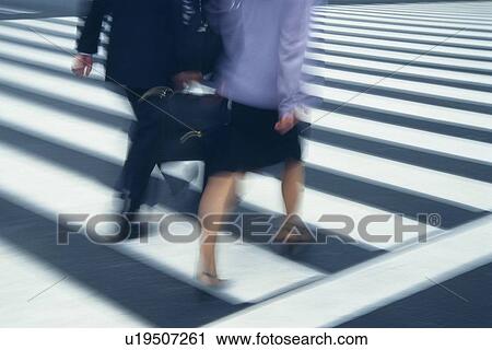 Stock Image - Two people crossing at the crosswalk, high angle view, blurred motion, Tokyo, Japan. Fotosearch