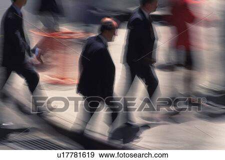 Stock Photo - Business people walking down on street, high angle view, blurred motion, New York City, NY, USA. Fotosearch
