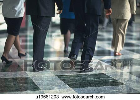 Stock Image - Business people walking on marble floor, rear view, New York City, NY, USA. Fotosearch