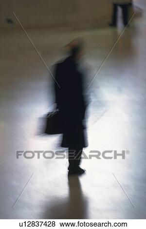 Stock Photo - Businessman standing and holding a bag, high angle view, blurred motion, New York City, NY, USA. Fotosearch