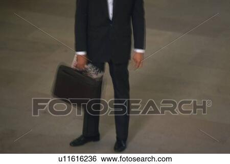 Stock Photograph - Businessman standing and holding a bag, high angle view, blurred motion, New York City, NY, USA. Fotosearch