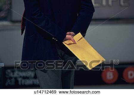 Businessman standing and holding a envelope, rear view, New York City, NY, USA View Large Photo Image Stock Photo - Businessman standing and holding a envelope, rear view, New York City, NY, USA. Fotosearch