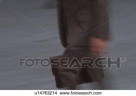 Picture - Businessman walking and holding a bag, side view, blurred motion, New York City, NY, USA. Fotosearch