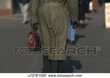 Stock Image - Businessman walking and holding a bag, rear view, New York City, NY, USA. Fotosearch