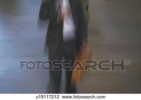 Stock Image - Businessman walking and holding a bag, front view, blurred motion, New York City, NY, USA. Fotosearch