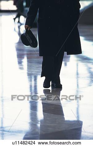 Businessman walking and holding a hat, front view, New York City, NY, USA View Large Photo Image Picture - Businessman walking and holding a hat, front view, New York City, NY, USA. Fotosearch