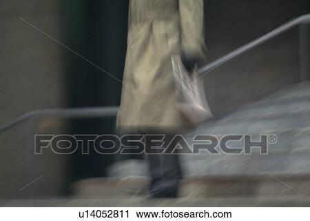 Stock Image - Businessman walking down the stairs, low angle view, blurred motion, New York City, NY, USA. Fotosearch