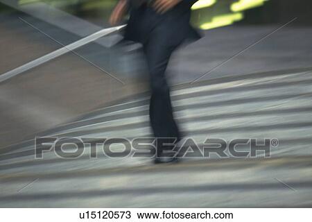 Stock Image - Businessman walking down the stairs, low angle view, blurred motion, New York City, NY, USA. Fotosearch