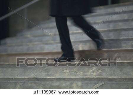 Stock Photo - Businessman walking down the stairs, low angle view, blurred motion, New York City, NY, USA. Fotosearch