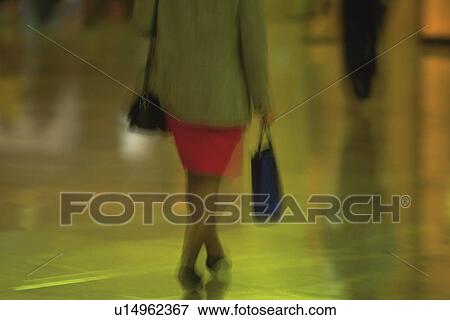 Stock Photo - Businesswoman walking and holding bags, rear view, New York City, NY, USA. Fotosearch