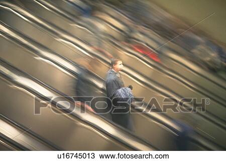 Stock Image - People riding escalators, high angle view, blurred motion, New York City, NY, USA. Fotosearch