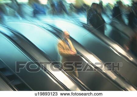 Stock Image - People riding escalators, high angle view, blurred motion, New York City, NY, USA. Fotosearch