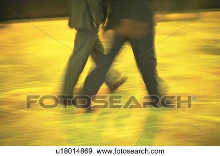 Stock Photo - Two men walking side by side, side view, blurred motion, New York City, NY, USA. Fotosearch