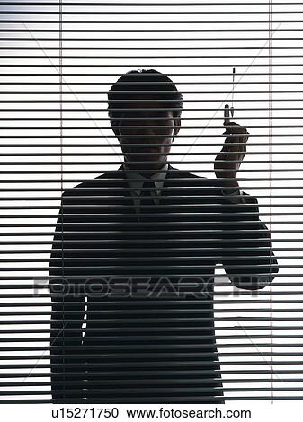 Businessman behind blind, holding a mobile phone, front view View Large Photo Image Stock Image - Businessman behind blind, holding a mobile phone, front view. Fotosearch