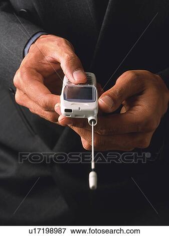 Stock Photo - Businessman pushing buttons of mobile phone, front view, close up. Fotosearch