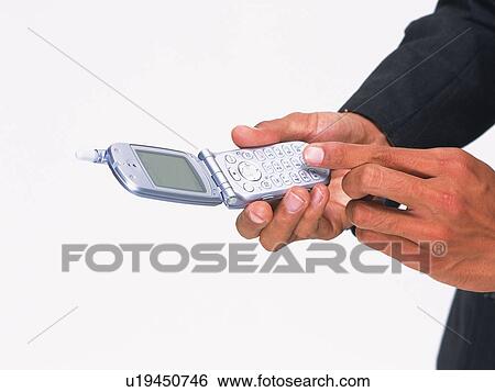 Stock Photograph - Businessman pushing buttons of mobile phone, high angle view. Fotosearch
