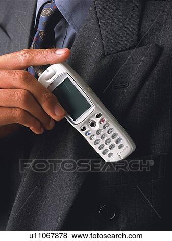 Stock Photo - Businessman putting mobile phone into pocket, front view, close up. Fotosearch