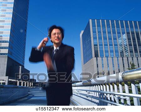 Businessman running and holding a mobile phone in the city, low angle view, blurred motion View Large Photo Image Stock Photo - Businessman running and holding a mobile phone in the city, low angle view, blurred motion. Fotosearch