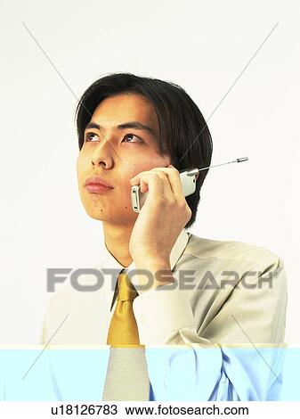 Stock Image - Businessman using a mobile phone and looking away, front view. Fotosearch