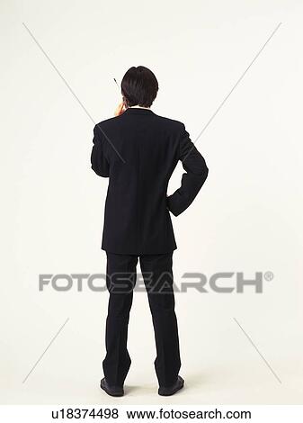Stock Photo - Businessman using a mobile phone, rear view. Fotosearch